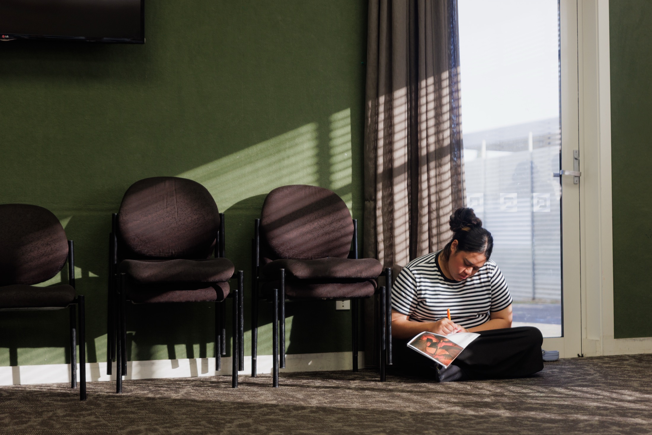 A young person journalling in warm light at a Youth Nu'u mentoring session in Palmerston North